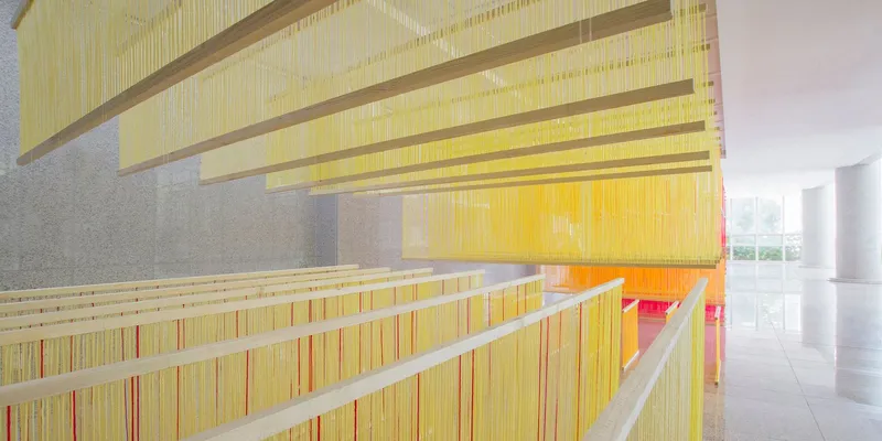 Angled view of the tiered yellow string installation reflecting on the polished floor