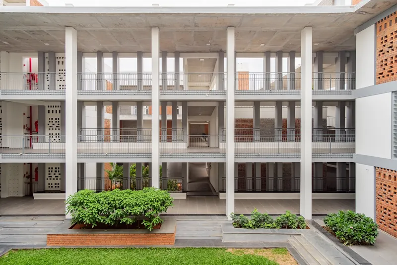 Courtyard view showing white columns supporting concrete slabs with planted beds and lawn at ground level