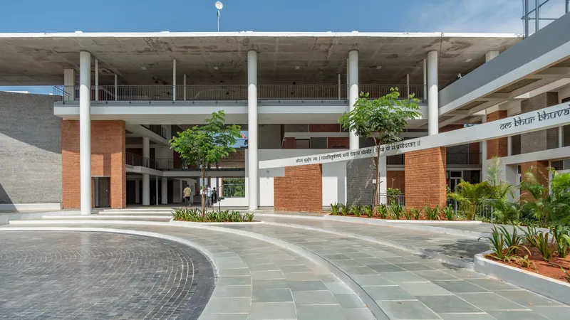 Paved courtyard with radial paving pattern and young trees framed by concrete slab and white columns