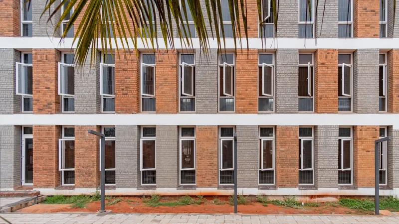 Repetitive brick facade with alternating terracotta and grey panels framed by palm fronds above