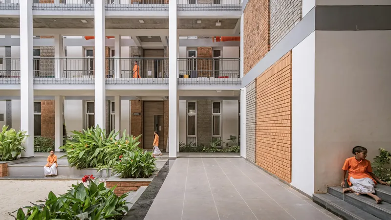 Shared courtyard with large pavers and planted beds flanked by white columns and brick walls with residents
