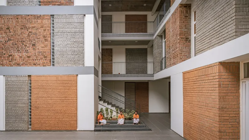 Multi-story courtyard view with staggered brick panels in varied colors and children seated on a stair