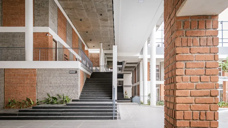 Interior staircase with black treads ascending between red brick column and patterned brick walls under concrete ceiling