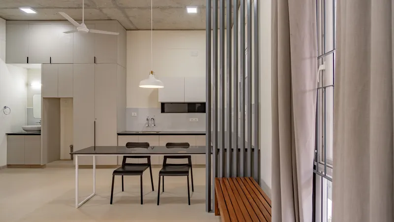 Open kitchen and dining area with vertical steel slat partition and pale wood cabinetry
