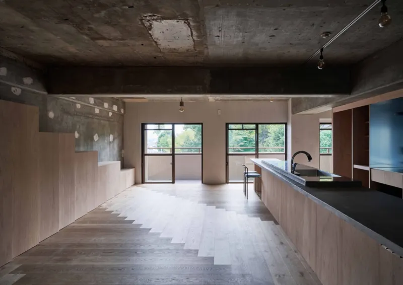 Split-level interior with timber kitchen counter and stepped floor beneath concrete ceiling beams