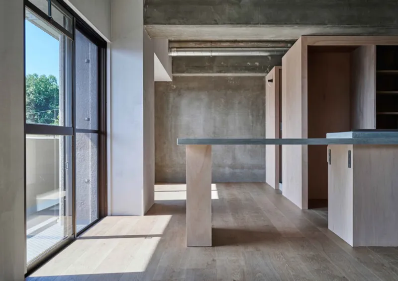 Open living space with cantilevered shelf and glazed doors opening to balcony in afternoon sunlight