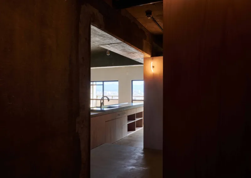 View through a doorway into the kitchen with pendant lighting illuminating the concrete soffit above