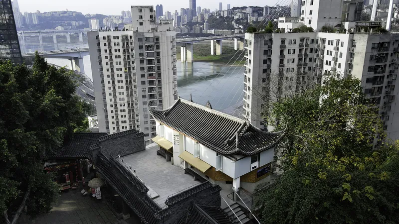 Elevated view of a preserved courtyard house with tiled roofs surrounded by residential towers