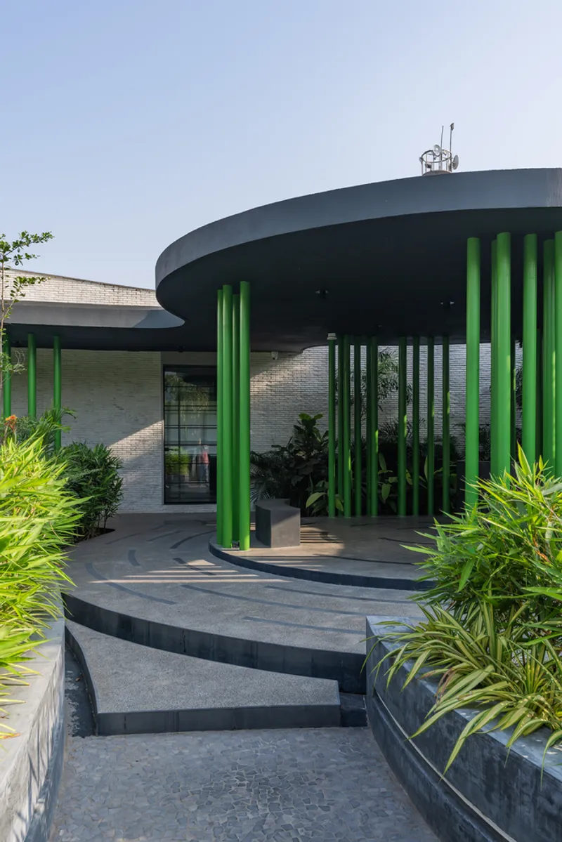 Entry steps leading up to the circular pavilion with green columns under an overcast sky