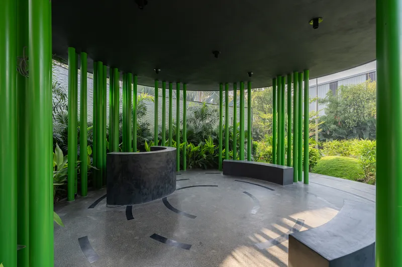 Semi-enclosed seating area enclosed by green columns with views to the surrounding garden