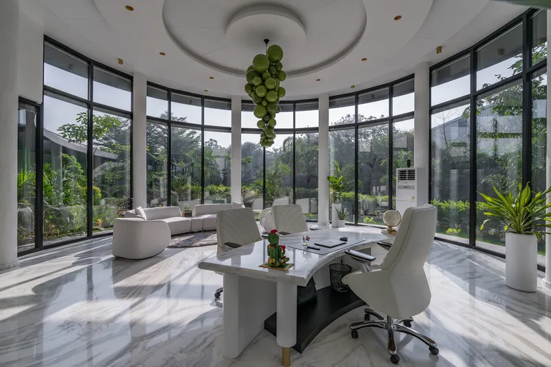 Curved glass wall enclosing a meeting space with white marble flooring and circular ceiling recess