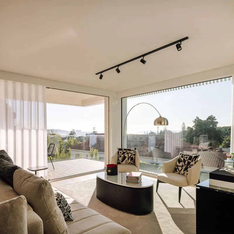 Living room with floor-to-ceiling glazing opening onto a terrace with distant rooftop views