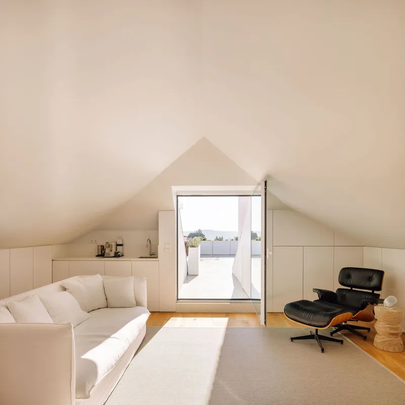 Attic room with sloped ceiling and central glazed door opening to a roof terrace