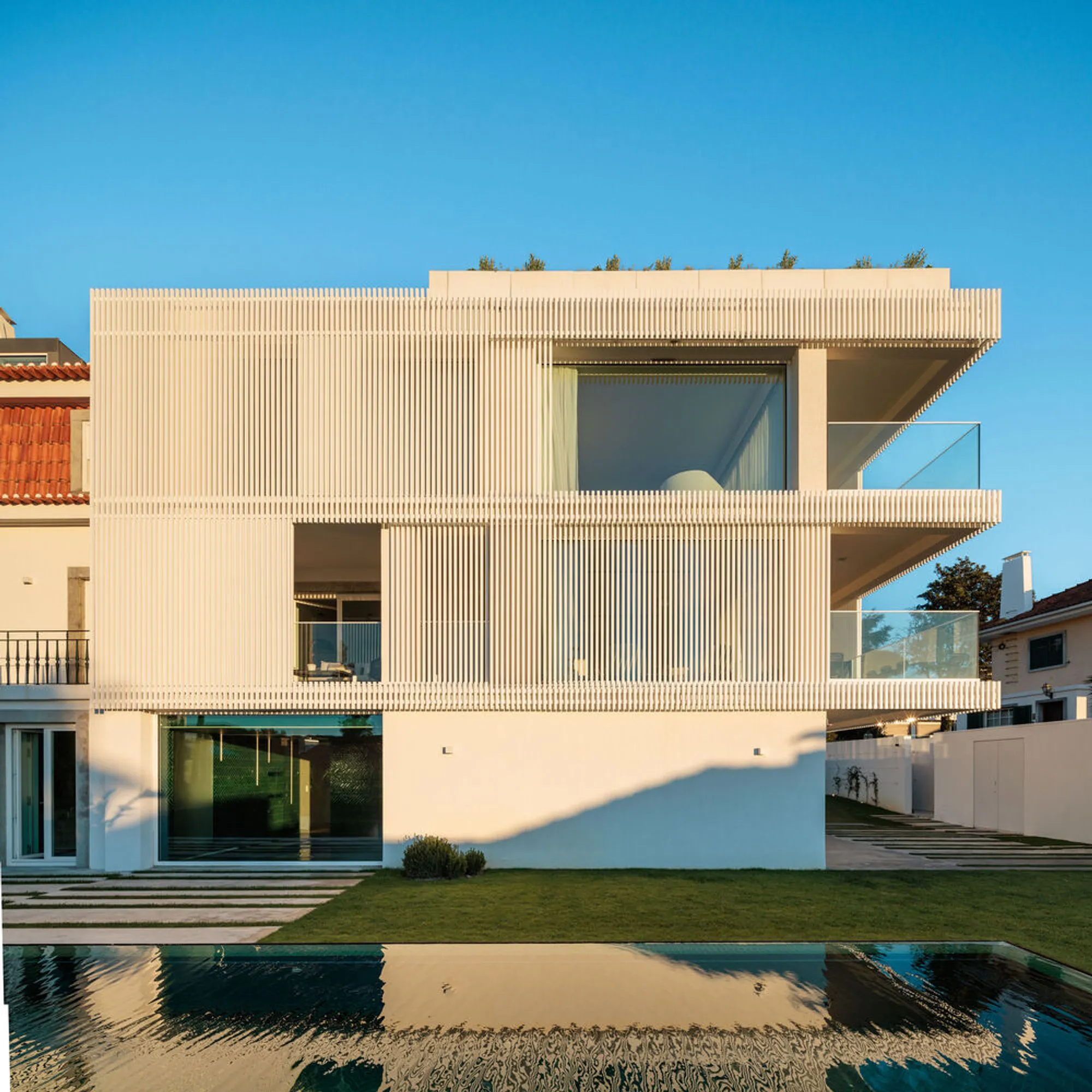João Tiago Aguiar Adds a White Louvered Volume to a 1950s Lisbon Twin House in Restelo