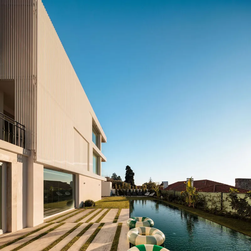 Rear facade overlooking swimming pool with striped lawn steps and neighboring rooftops beyond
