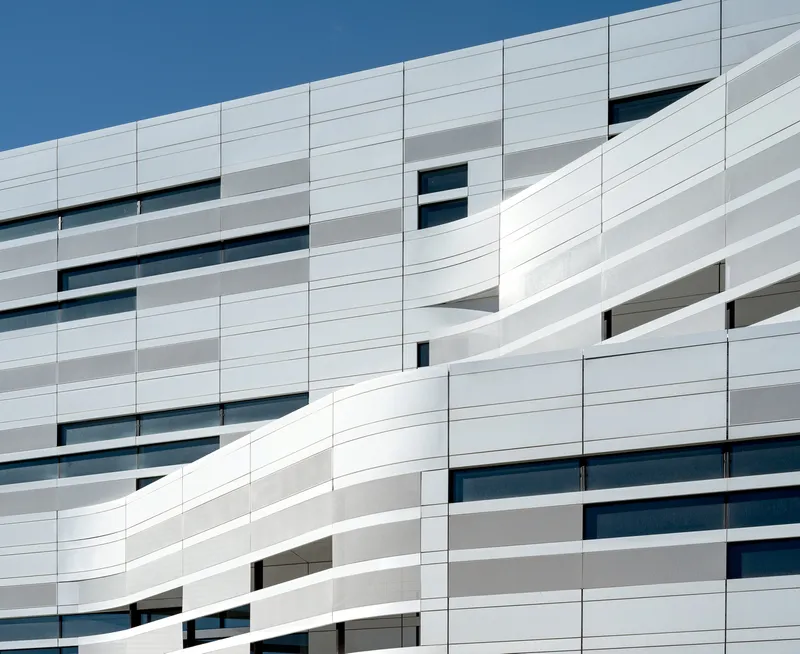 White ribbed panel facade with horizontal ribbon windows under a clear blue sky