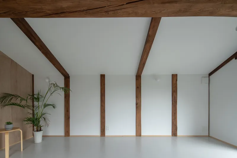 Interior space with exposed timber columns and beams crossing a white ceiling above pale grey flooring