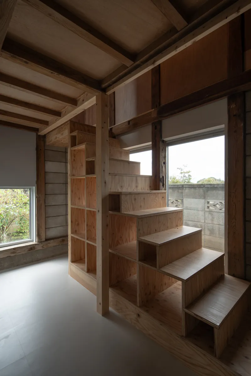 Integrated timber staircase with built-in shelving beneath exposed ceiling beams and two windows