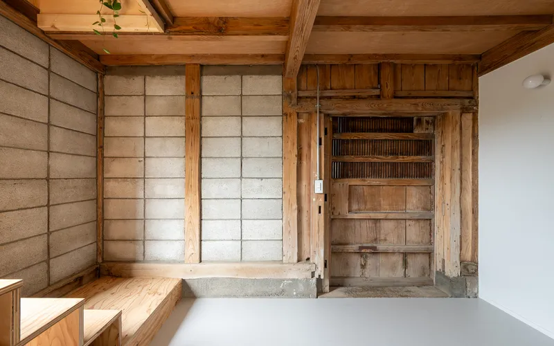 Room featuring paper sliding screens, exposed timber structure, and a recessed alcove with slatted shelving