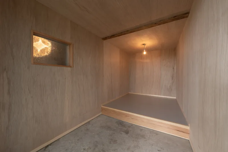 Small alcove lined in pale timber with raised platform and backlit translucent panel