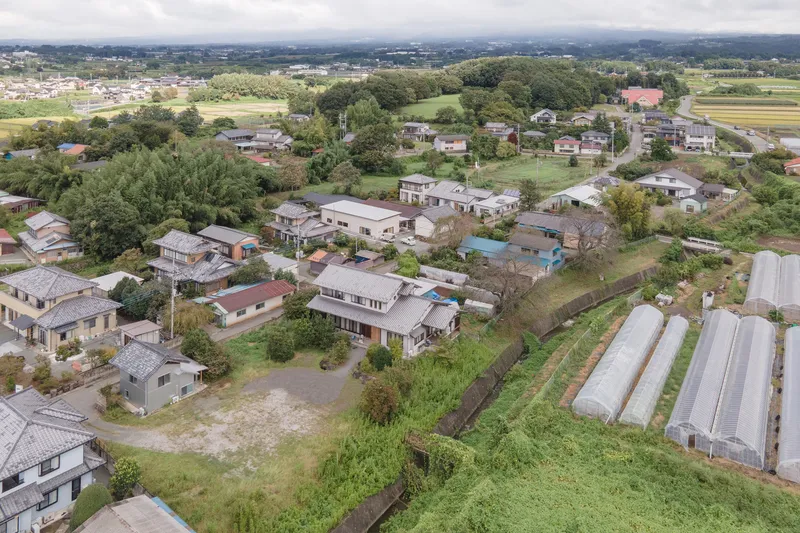Aerial view of residential neighborhood with houses scattered among fields and greenhouses