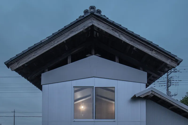 Corner window beneath traditional tiled eaves glowing at twilight