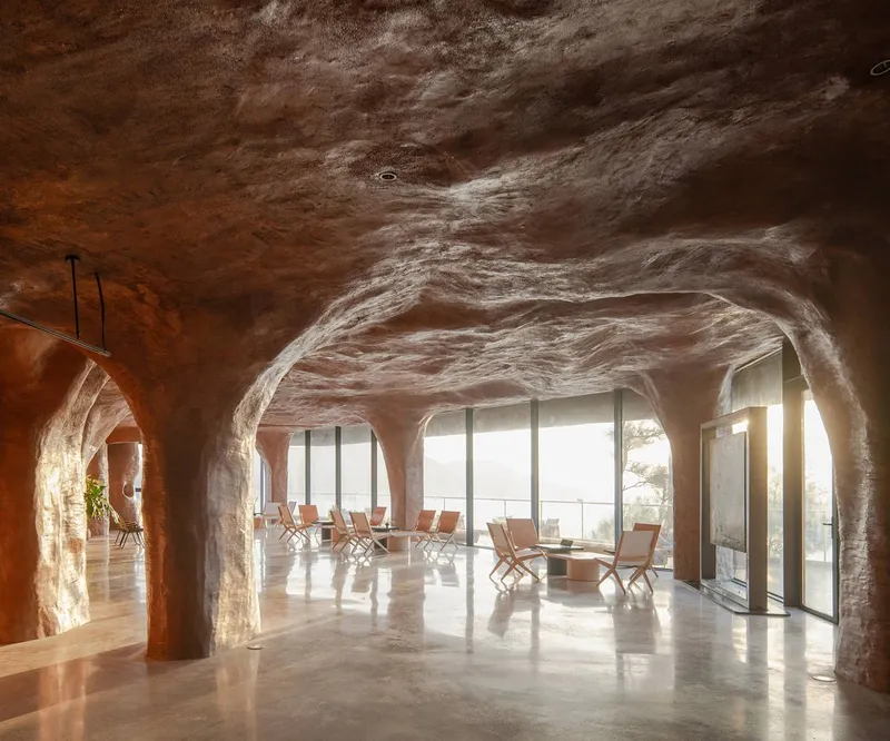Cave-like interior with sculpted ceiling and arched openings framing ocean views through floor-to-ceiling glass