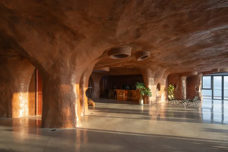 Sculpted earthen columns and arched passages illuminated by warm artificial light at sunset