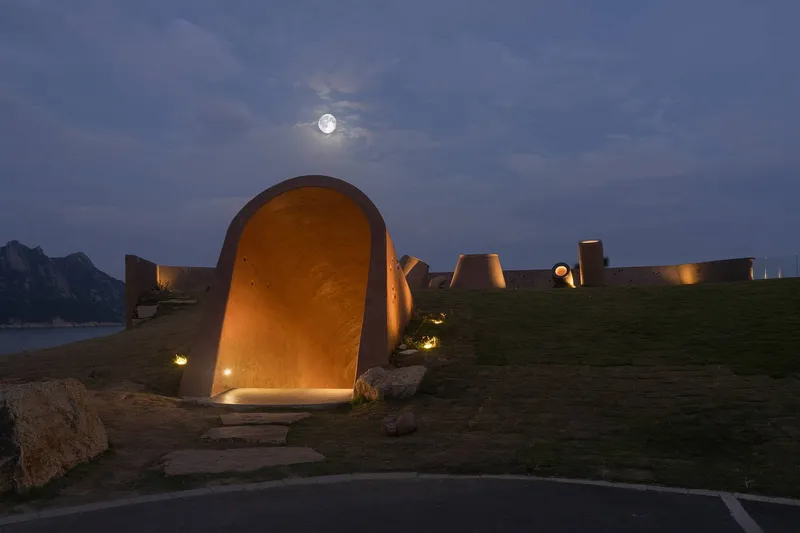 Illuminated arched entry portal with stone steps under a full moon at twilight