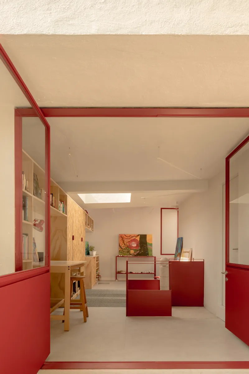 Layered view through red portal frames showing plywood shelving and concrete floors in afternoon light