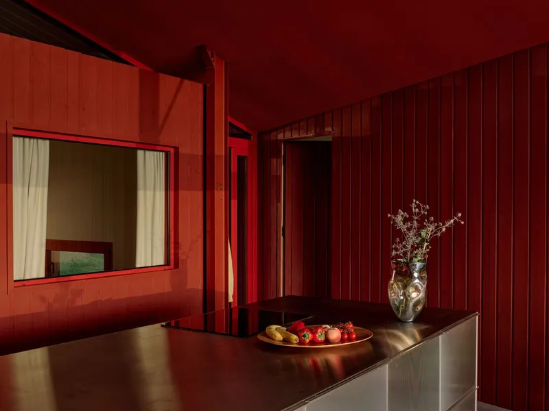 Interior window opening in vertical red timber cladding illuminated by warm evening light