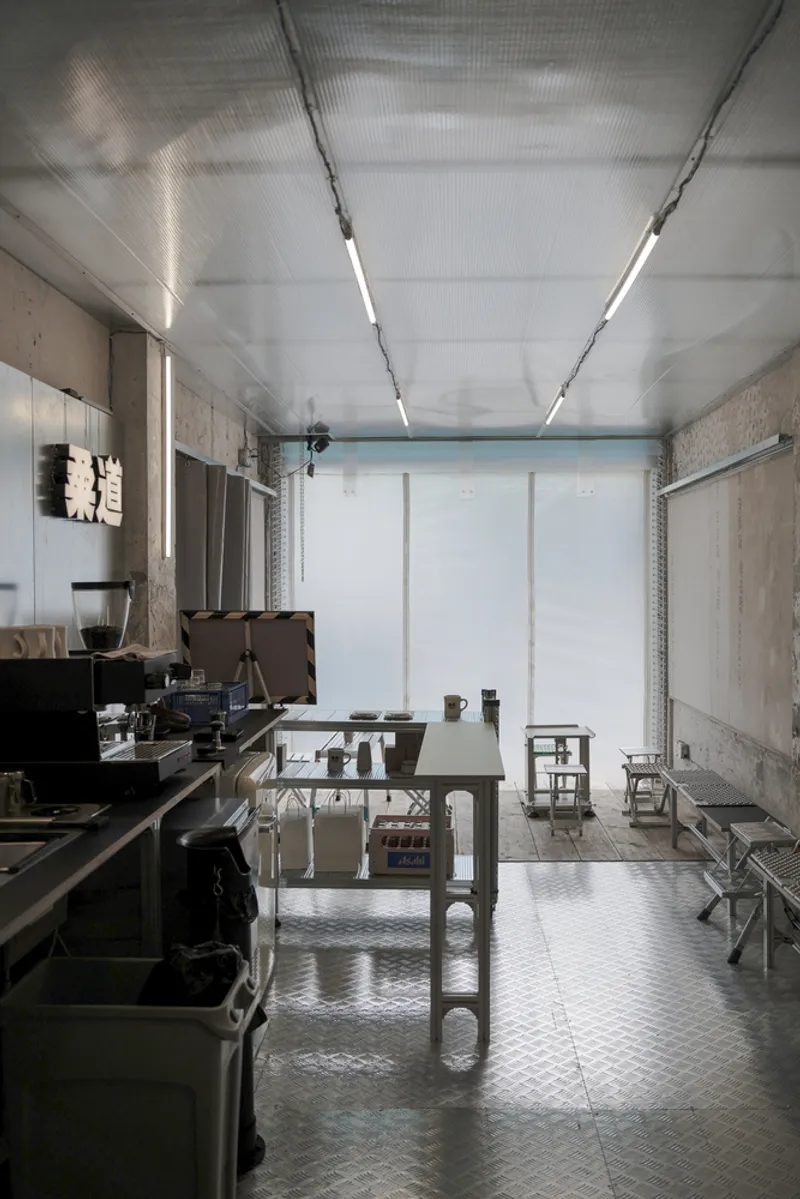Long view of workshop interior with linear fluorescent lighting and translucent roller shades at the entrance