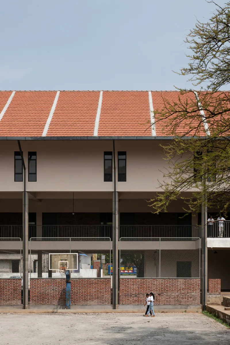Exterior courtyard elevation showing the terracotta tile roof above a pale rendered wall with students walking below