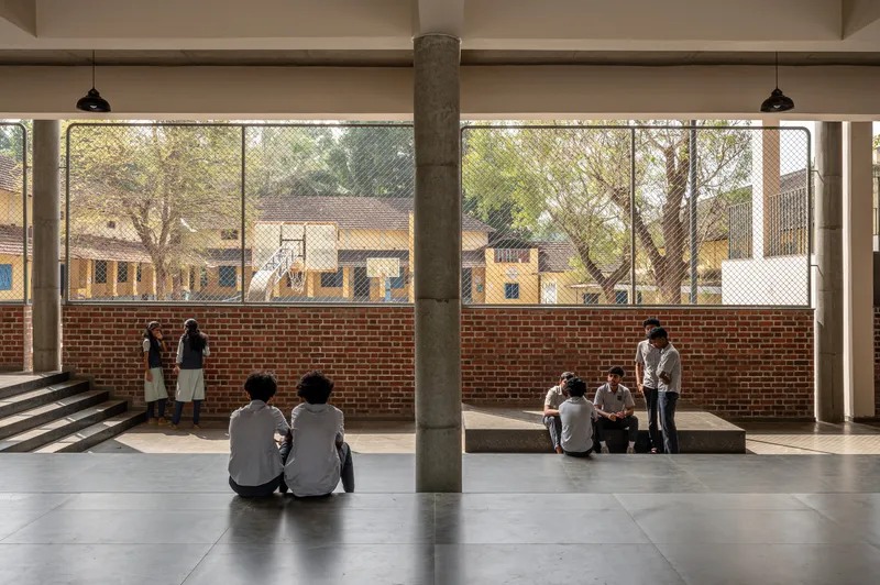 Corridor with concrete column, brick half-wall and wire mesh openings where students gather