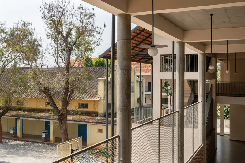 View from an upper walkway through cylindrical concrete columns toward neighboring buildings and trees