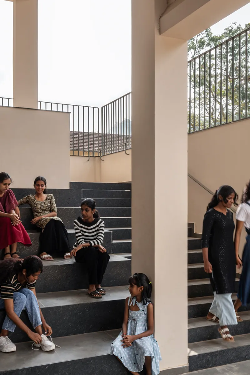 Interior staircase with dark stone treads where visitors sit and stand beneath white columns