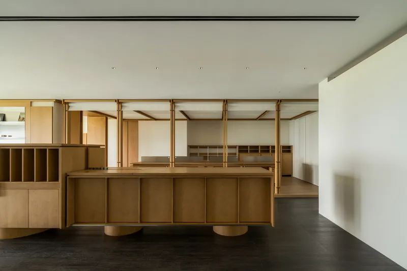Interior showing suspended plywood island and timber frame structure over dark flooring