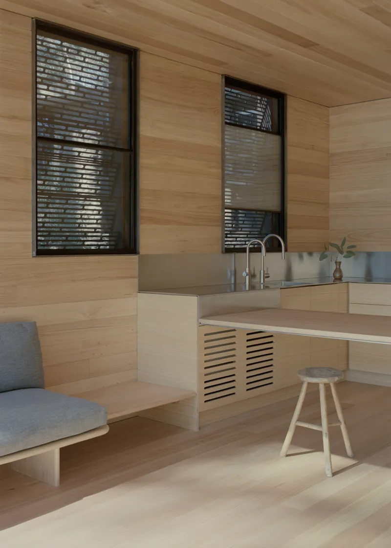 Kitchen bench with stainless steel sink and timber island with louvered panel beneath tall windows with blinds