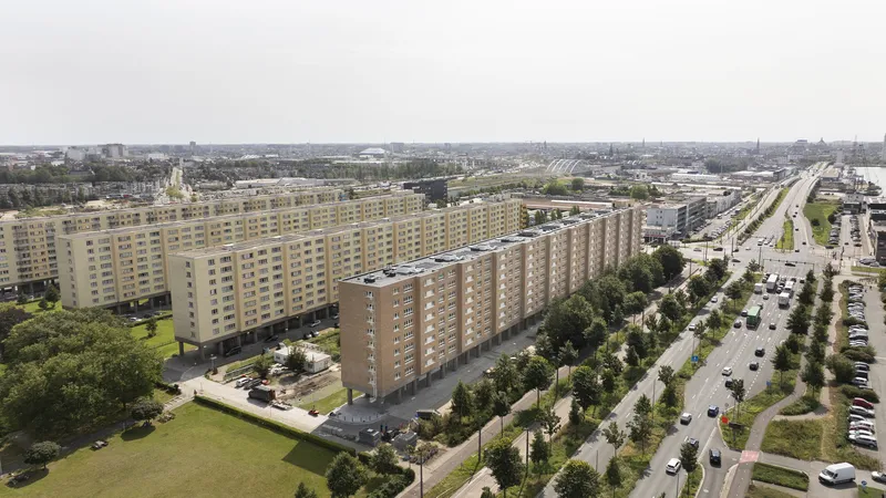 Aerial view of linear slab blocks with yellow and tan facades in a landscaped residential district