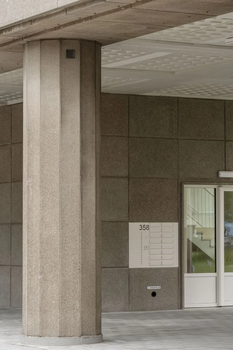 Building entrance with precast concrete column and directory panel beside glazed door