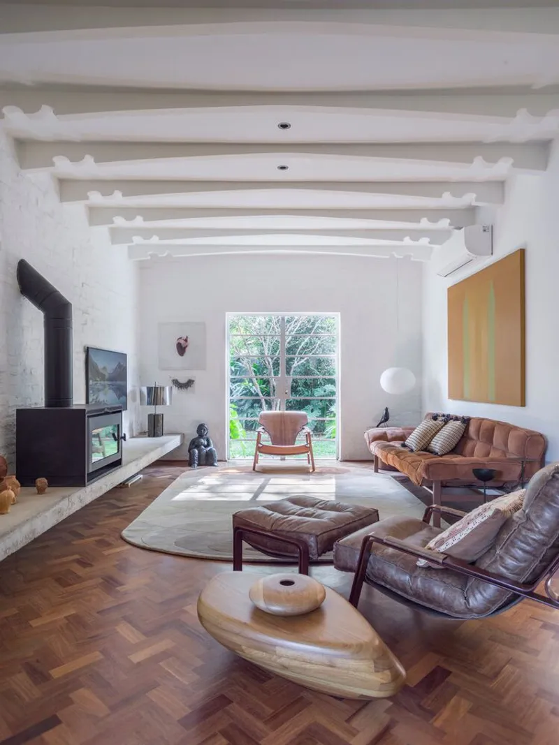 Living room with white painted exposed beams and herringbone wood floor in natural daylight