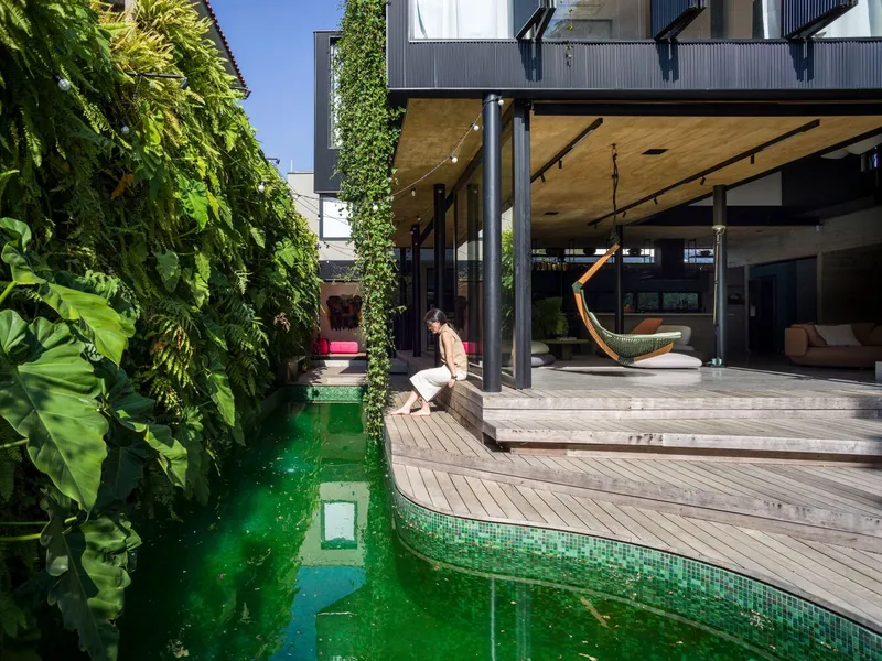Timber deck wrapping around a narrow pool with green mosaic tile and vertical planted walls
