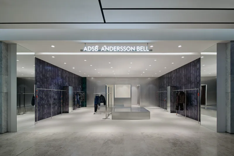 Storefront entrance with dark wood wall panels flanking a central mirrored volume under recessed ceiling lights