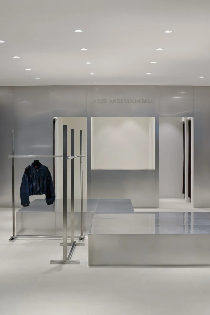 Freestanding chrome garment rack with a single jacket displayed against translucent glass panels