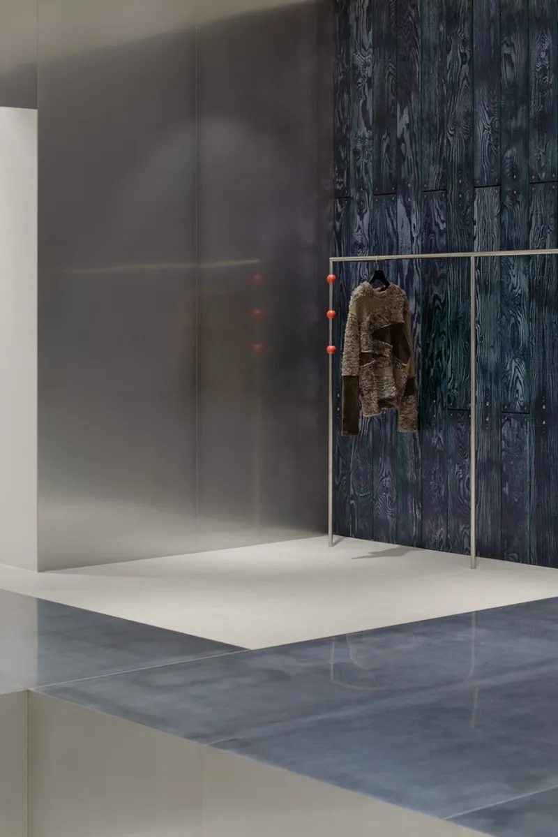 Translucent grey partition alongside dark wood paneling with a jacket hanging from a metal rail
