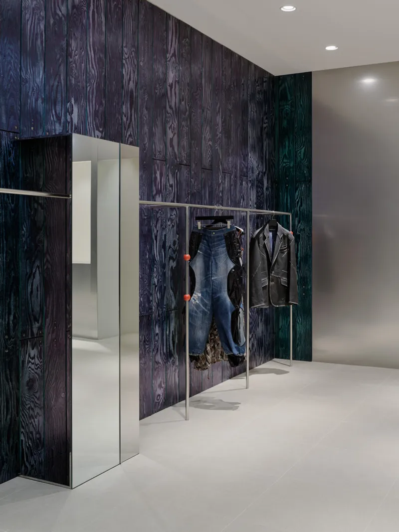 Corner view of dressing area with dark woodgrain panels and freestanding chrome garment racks