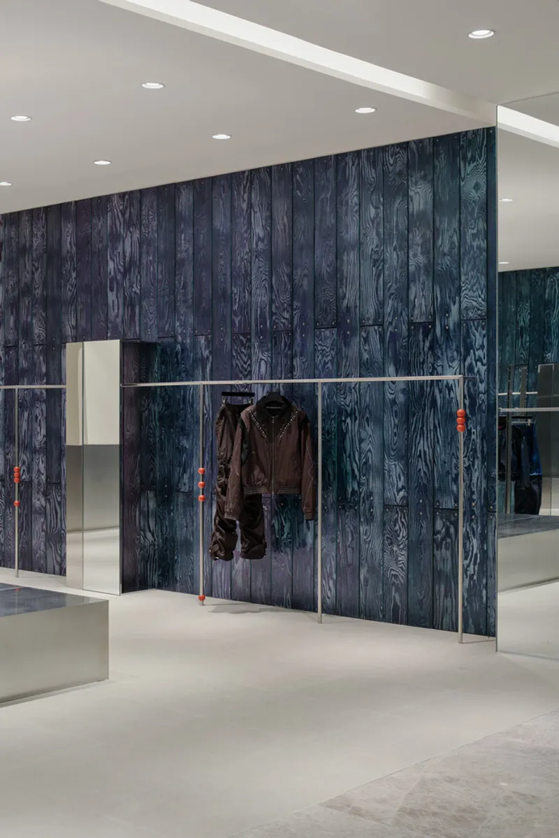 Dark wood-grain paneled wall with horizontal metal garment rail displaying a single jacket