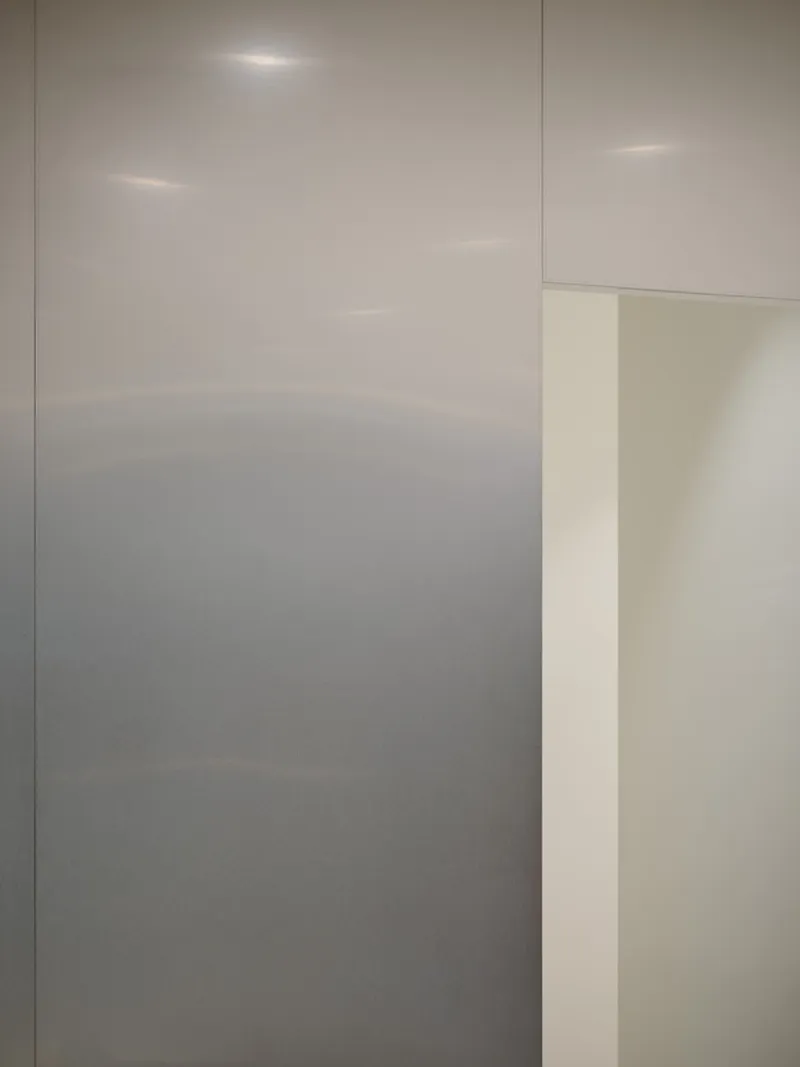 Minimal white wall panels meeting at an illuminated corner with recessed light washing the surface