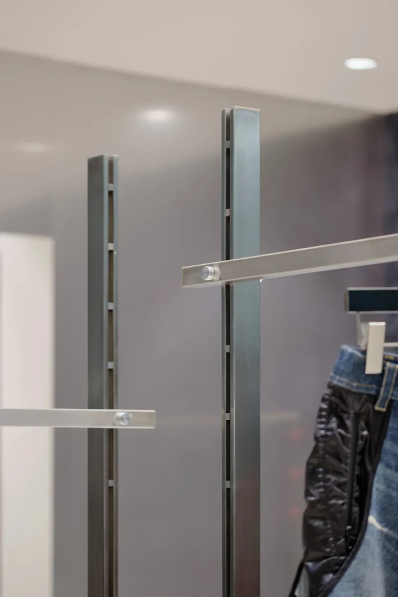 Close-up of slotted metal uprights and horizontal chrome rails in retail display system