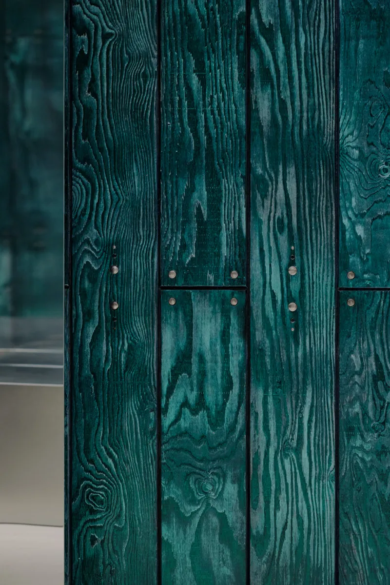 Close-up of teal stained wood panels with exposed metal hinges and wood grain texture